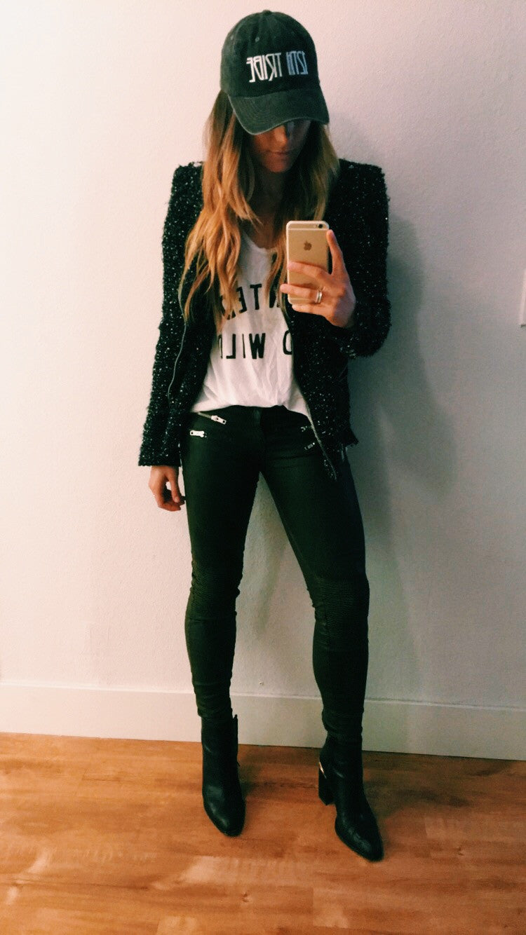 Mirror selfie in a 12th Tribe cap, sequined black jacket, white graphic tee and skinny jeans.