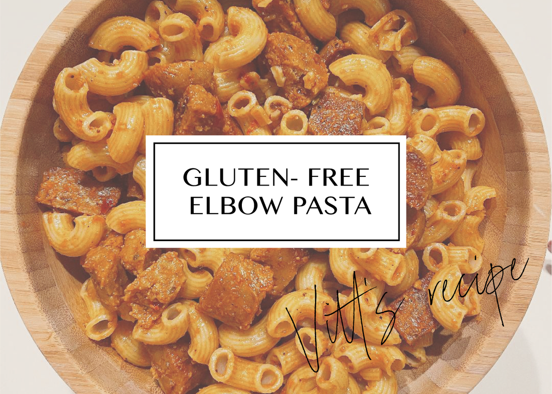 Gluten-free elbow pasta in roasted red pepper sauce with vegan sausage, in a wooden bowl.