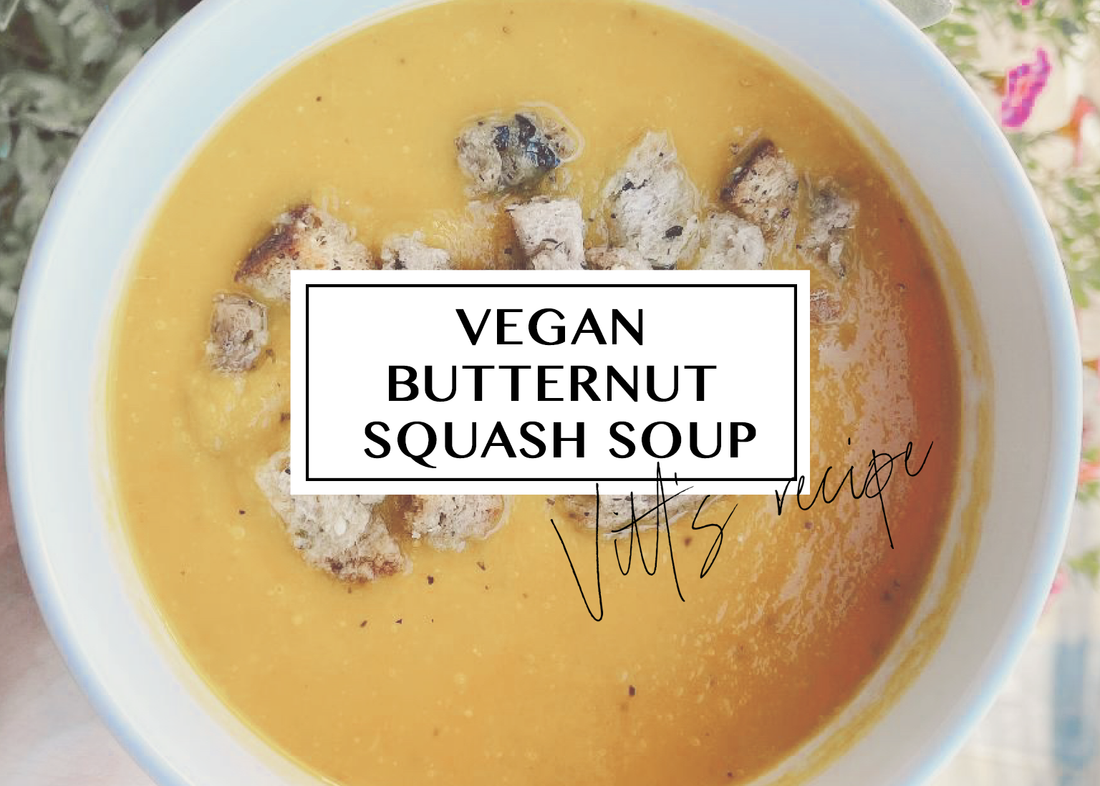 Creamy vegan butternut squash soup topped with herbed croutons in a white bowl.
