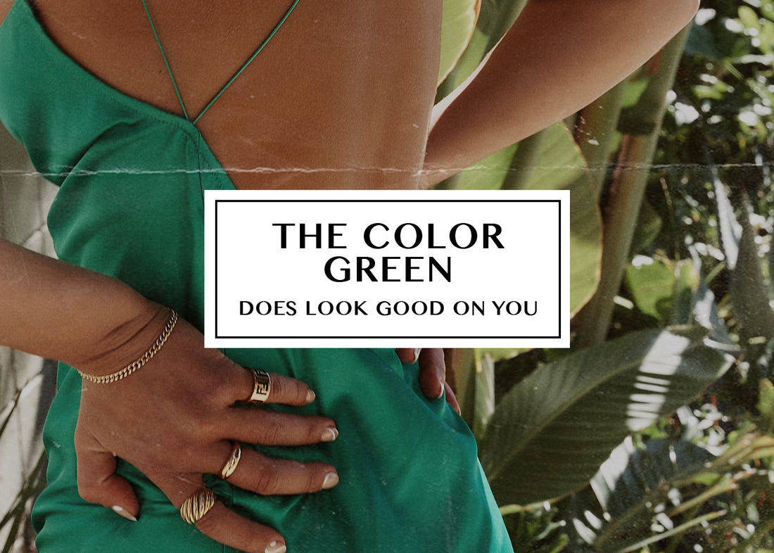 Green backless slip dress styled with gold rings, worn against lush tropical foliage.