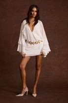 Model wearing the 12th Tribe Alice White Chiffon Mini Dress in crisp white, featuring a lightweight chiffon fabric, a fitted mini silhouette, styled with a statement belt, necklace, and heels for all bachelorette parties, wedding events, brunches, and evening outings.