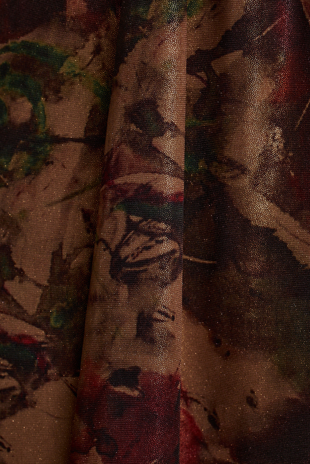 Close-up of shimmering metallic floral print fabric in burgundy, bronze, and deep green tones.