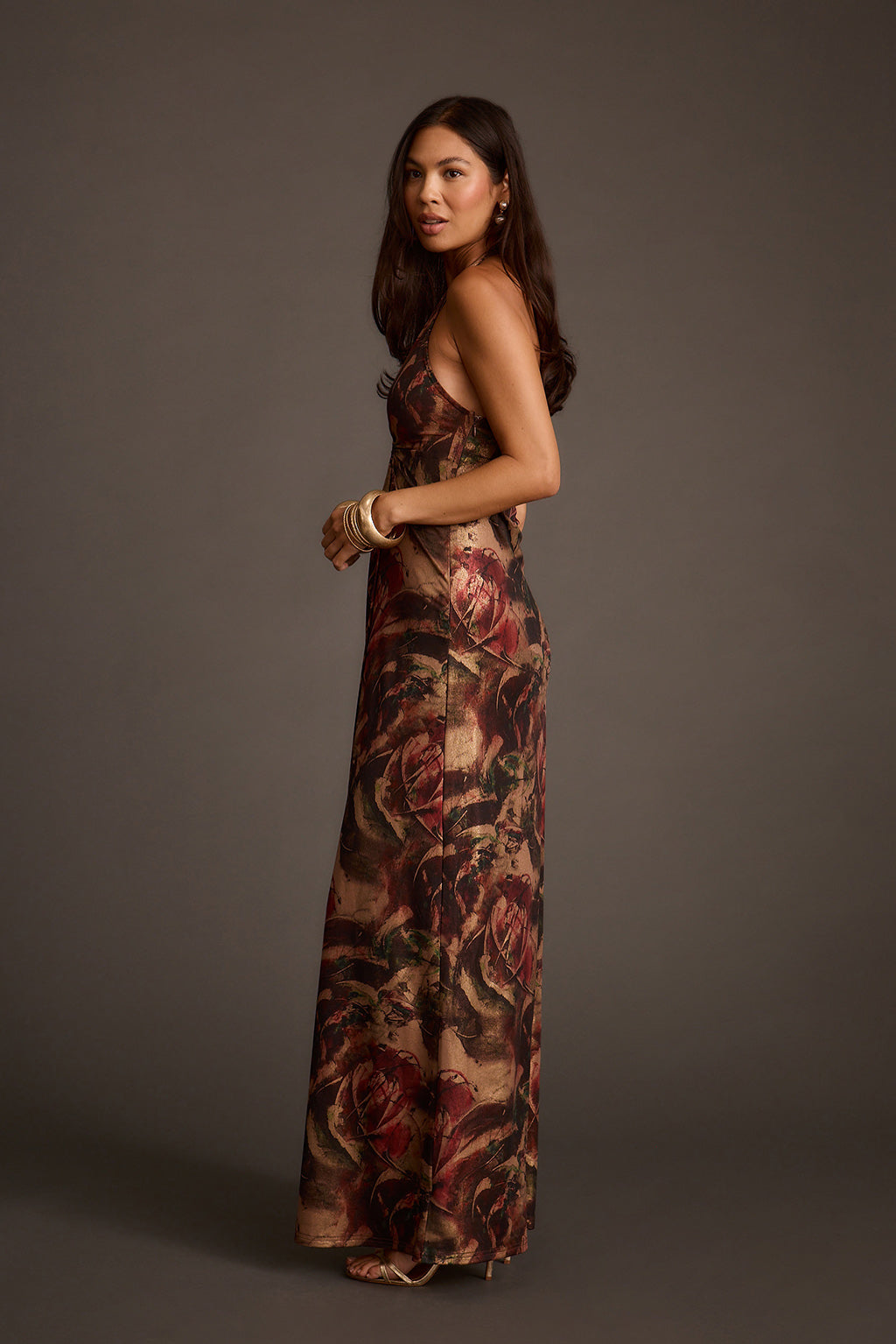 Side view of a metallic floral maxi dress with a floor-length silhouette and side slit.