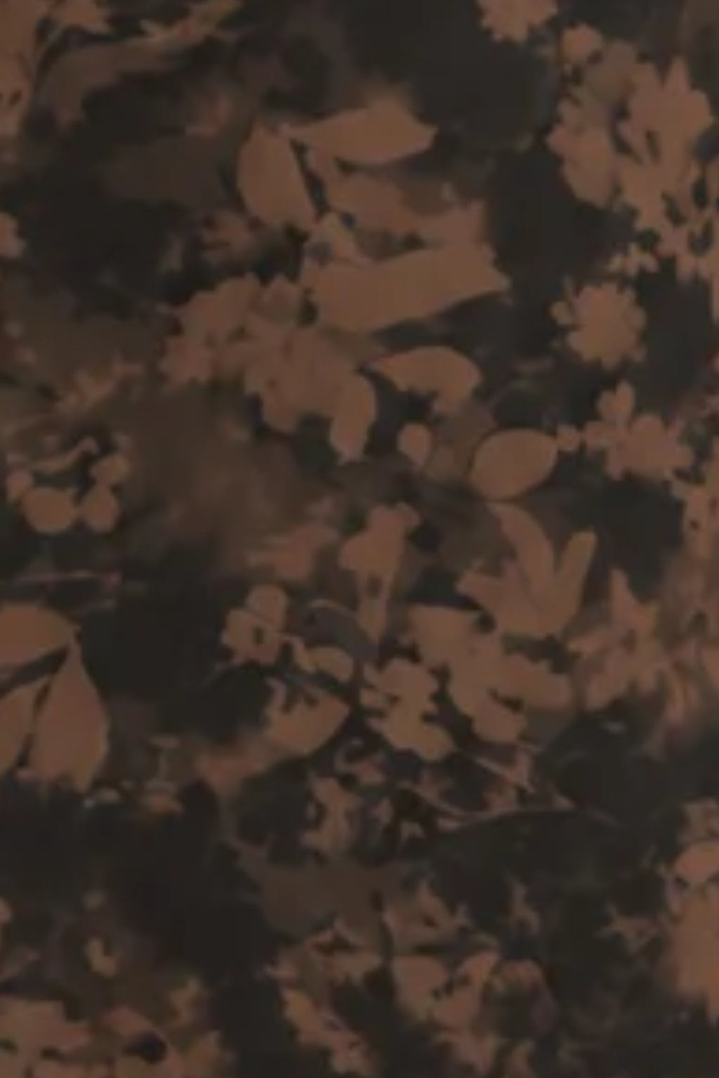 Fabric detail of a floral mesh maxi dress showing a blurred brown botanical print on a black background