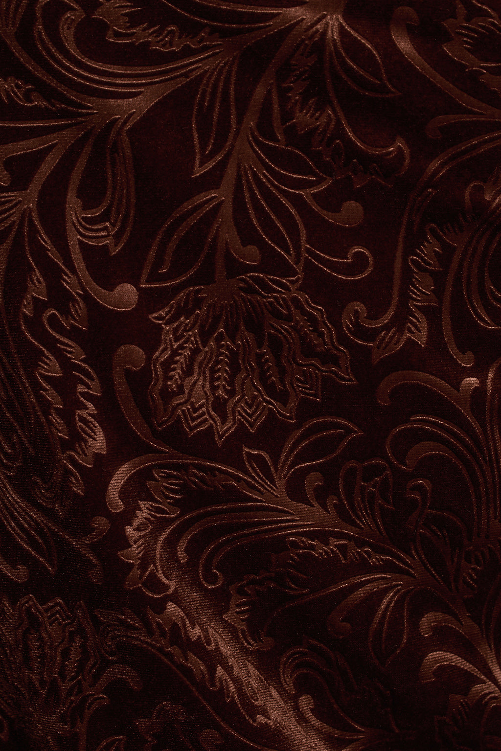 Rust embossed velvet fabric detail showing scroll print texture and fringe trim close-up