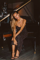 Model wearing the 12th Tribe Amora Mocha Floral Mesh Maxi Dress, featuring a sheer floral mesh overlay, a sexy maxi silhouett, styled with strappy heels and delicate jewelry for weddings, garden parties, drinks with the girls, and evening events.