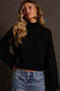 Cropped sweater in black with mock turtleneck and bell sleeves, styled with barrel jeans