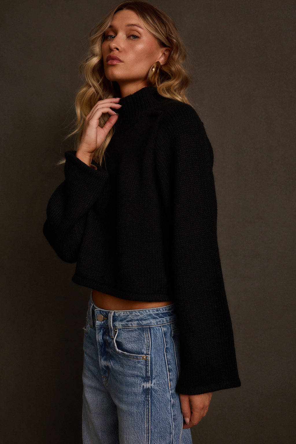 Fall sweater side angle with bell sleeve detail and cropped hemline above waist