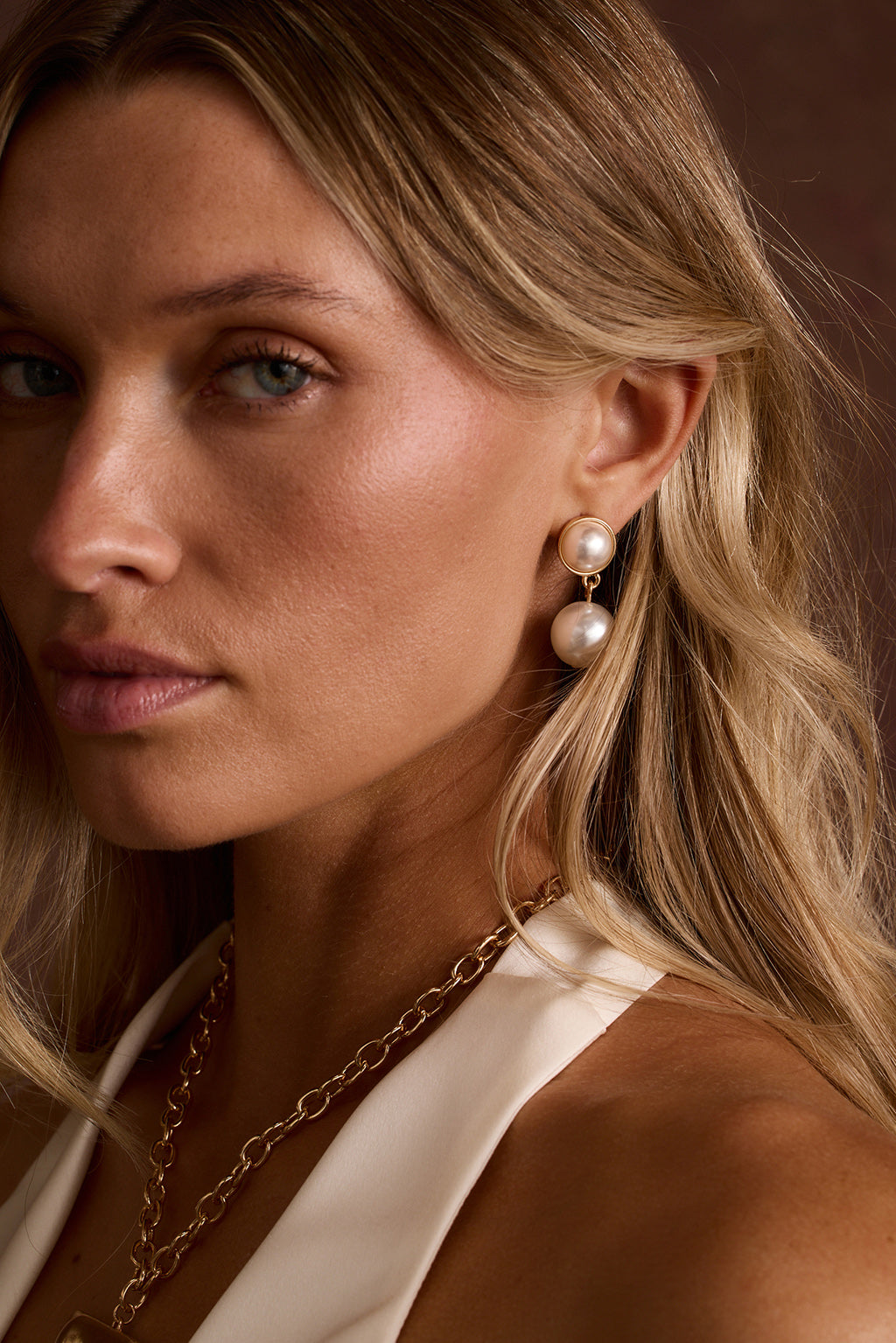 Bellami double pearl drop earrings in gold worn with a chunky chain necklace.