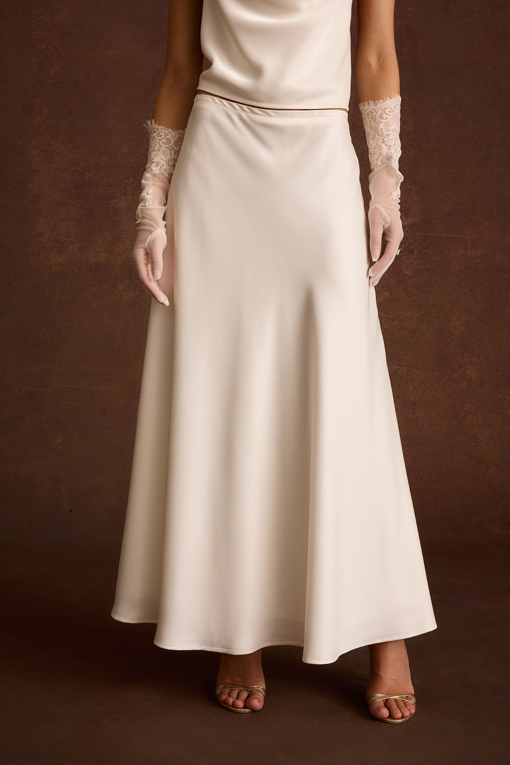 Close-up of an ivory satin maxi skirt with a smooth A-line silhouette.