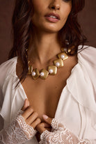 Model wearing the 12th Tribe Bloom Pearl Choker in lustrous gold and pearl colors, featuring a chunky statement necklace of your dreams, gold-tone clasp, styled layered with other necklaces or solo for weddings, festivals, and everyday chic looks