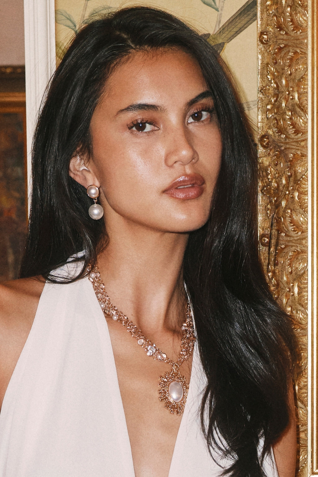 Double pearl drop earring worn with a layered pearl and crystal pendant necklace.