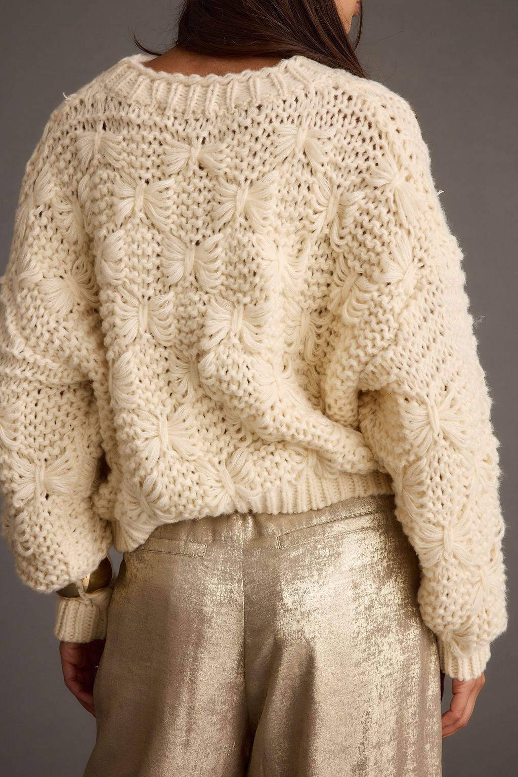 Back view of the cream knit sweater showing the silhouette and fit.