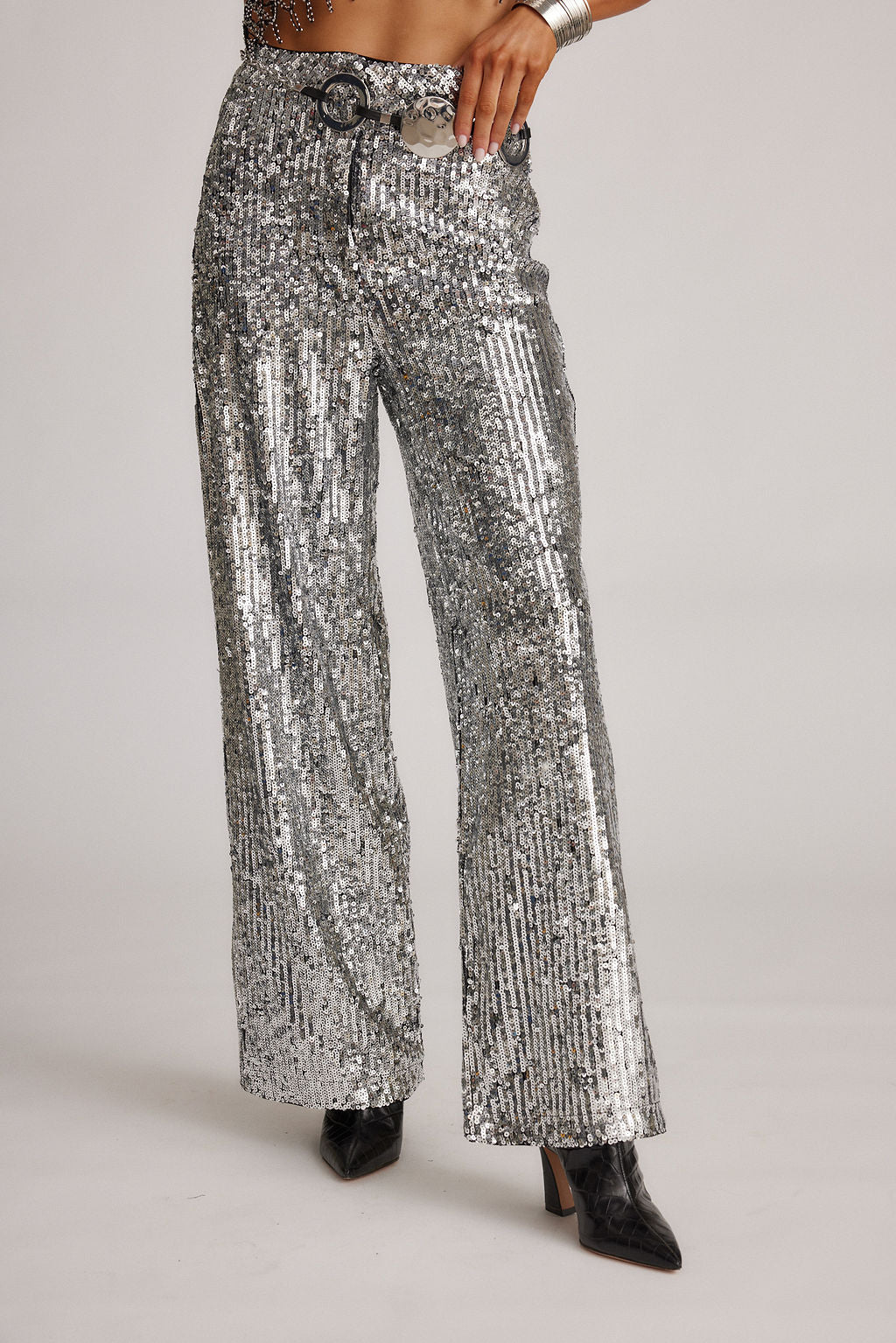 Full-length view of the silver trousers showing the drape and movement.