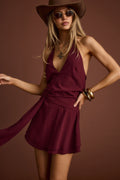 Model wearing the 12th Tribe Canyon Bloom Mulberry Mini Dress, a chiffon mini dress featuring adjustable back neck halter ties and a draped asymmetrical faux belt detail, perfect for summer soirées, festival-ready looks, and stylish warm-weather outings