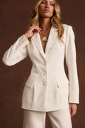 White tapered blazer worn with matching trousers and a gold pendant necklace, on-model.