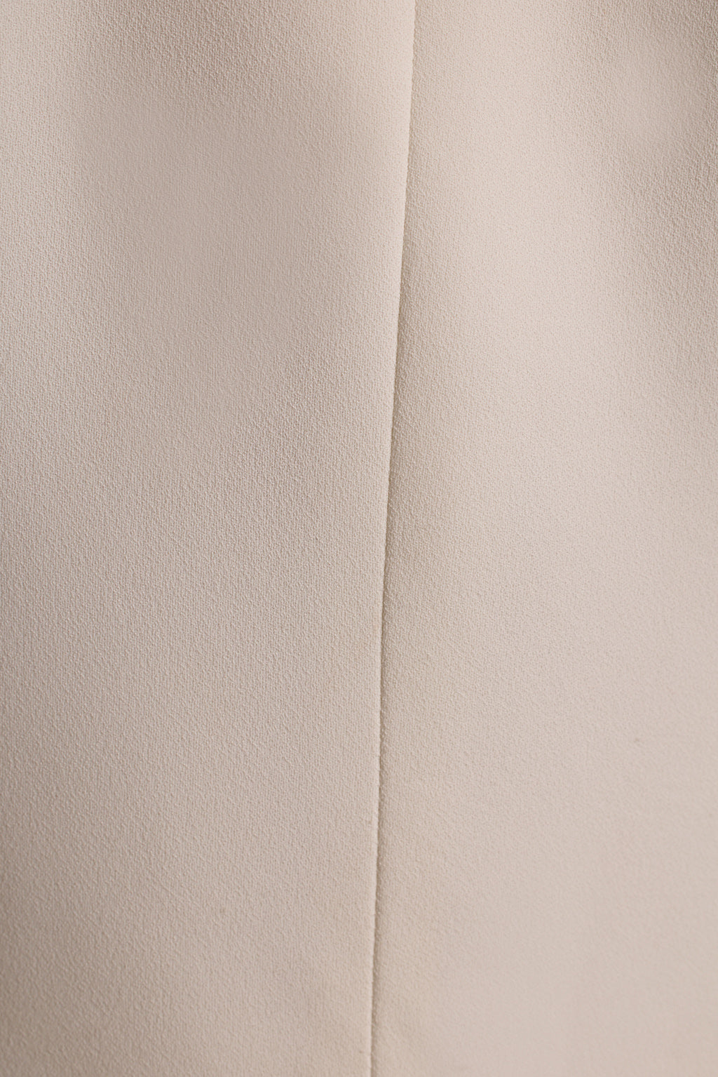 Close-up of the cream crepe fabric and center seam on a white tapered blazer.