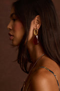 Gold drop earrings with a textured open link topper and a faceted deep-red teardrop stone.
