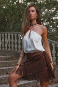 Espresso satin fringe sarong skirt styled with a cream halter top on garden steps.