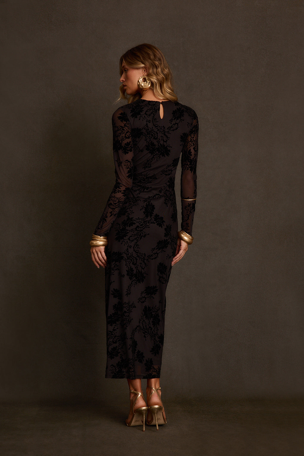 Black velvet dress back view showing sheer mesh panels and fitted floor-length shape