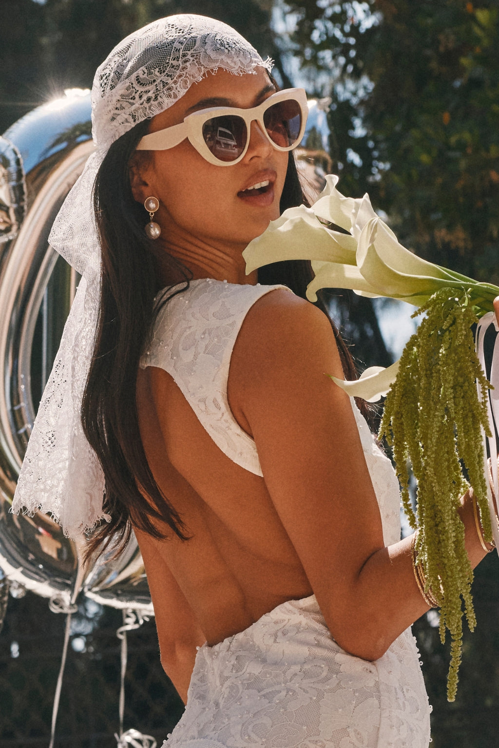 Lace kerchief headscarf worn with cat-eye sunglasses and a pearl drop earring.