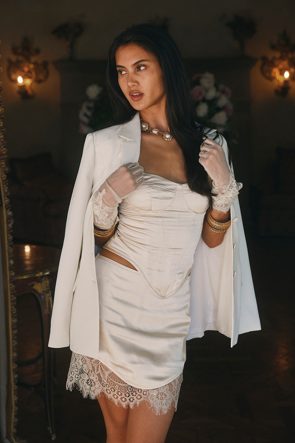 Ivory satin corset mini dress with boned bustier bodice, cut-out waist, and eyelash lace hem.