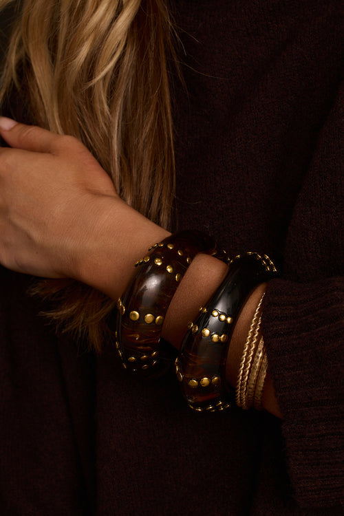 Women's bangle bracelet set close-up showing tortoiseshell pattern and hammered gold studs