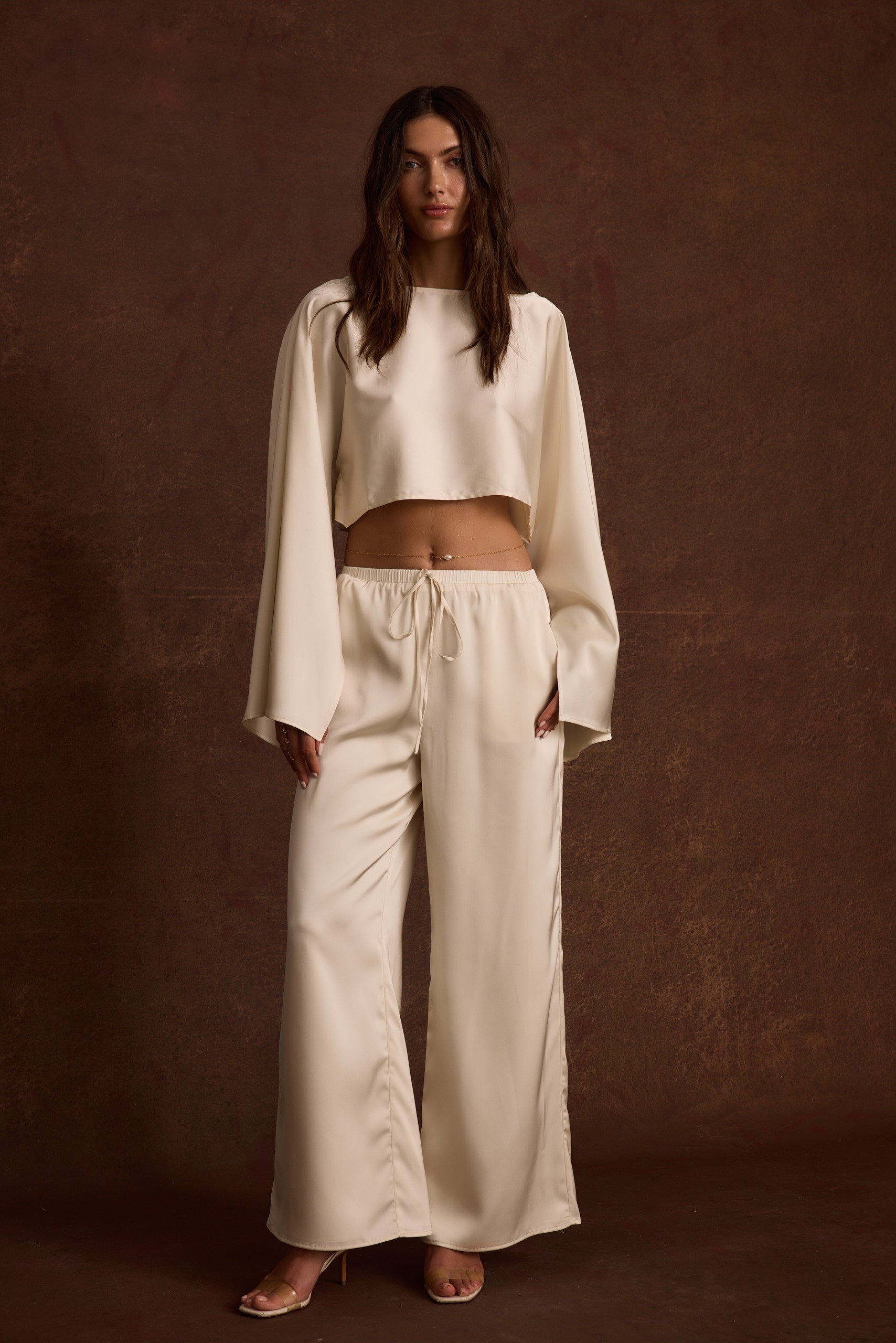 Lifestyle shot of the cream pants styled for day-to-night versatility.