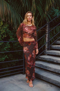 Model wearing the 12th Tribe Clear Breeze Mulberry Floral Mesh Top with the matching Julia Mulberry Floral Mesh Maxi Skirt, featuring a sheer floral mesh design, a cropped top, and a flowing maxi skirt, styled with heels for bachelorette parties, weddings, garden parties, and bachelorette evening events