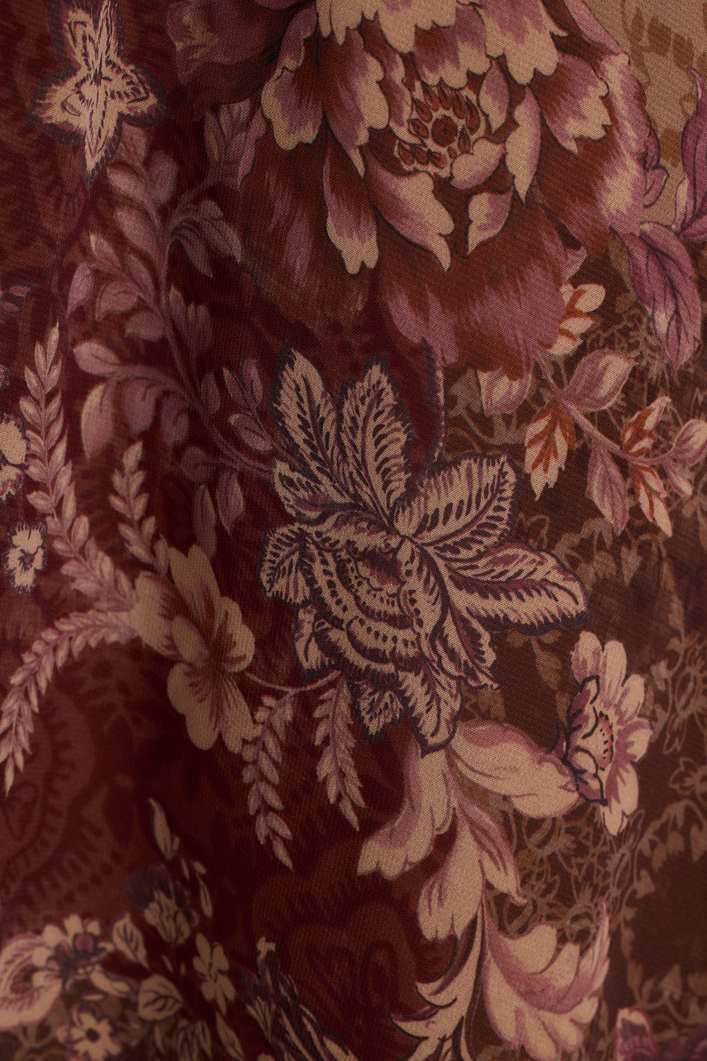 Close-up of berry floral chiffon fabric in burgundy, mauve, and tan tones.