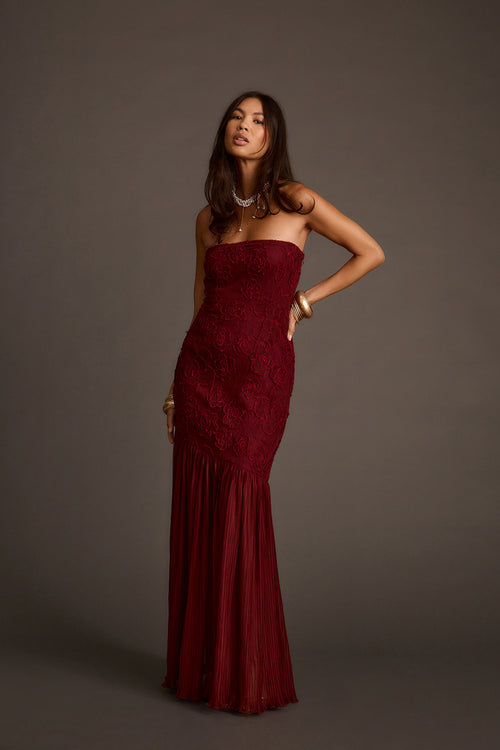 Front view of a strapless burgundy rose lace maxi dress with a pleated mermaid hem.