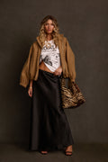 Satin maxi skirt in black styled with graphic tee, tan bomber jacket, and zebra print tote