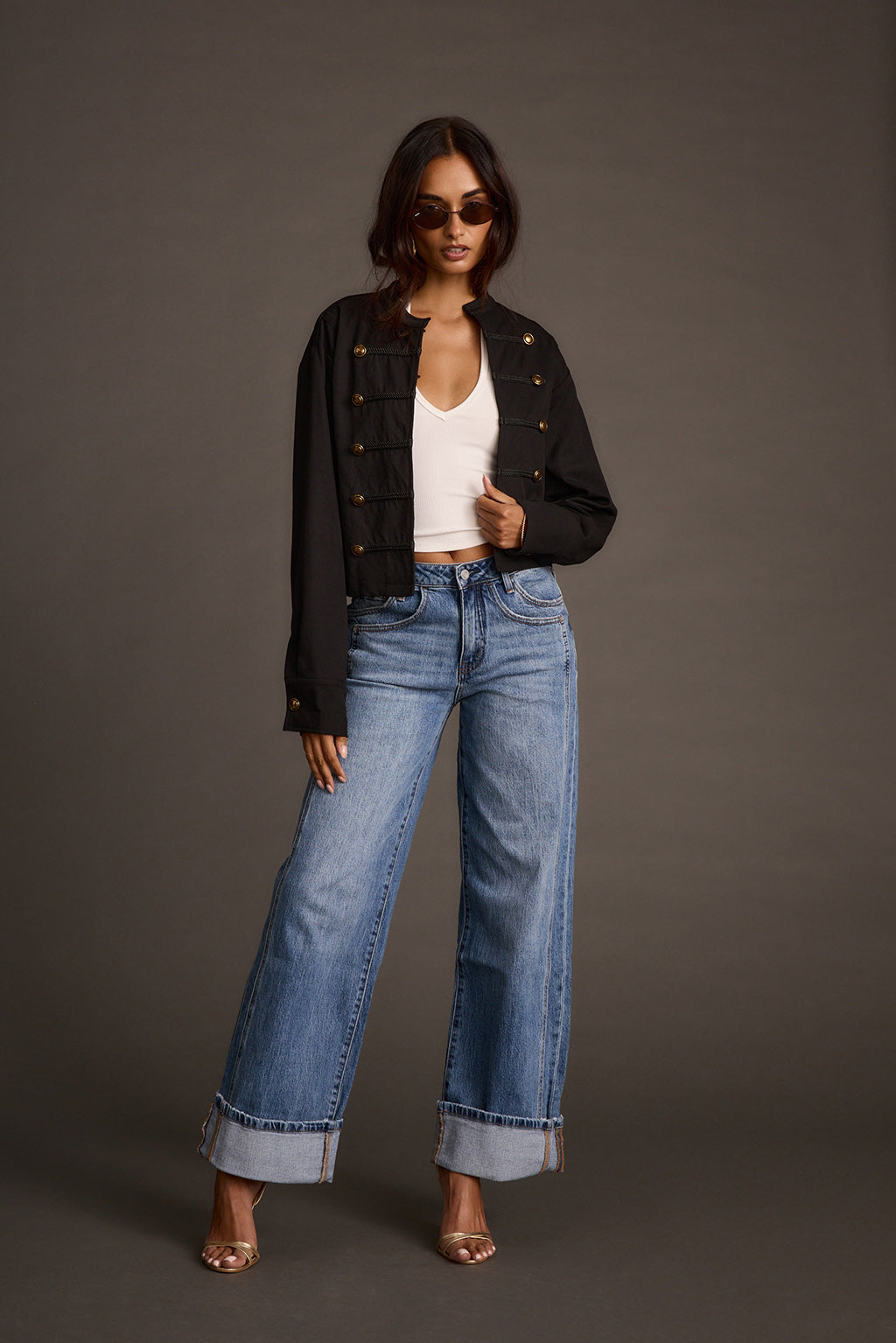 Full-length view of a woman in a black drummer jacket, white top, and cuffed wide-leg jeans