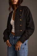 Close-up of a black drummer jacket's gold buttons and braided trim over a white tank top