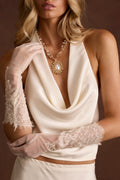Sheer white lace trim gloves styled with a cream satin cowl-neck top.