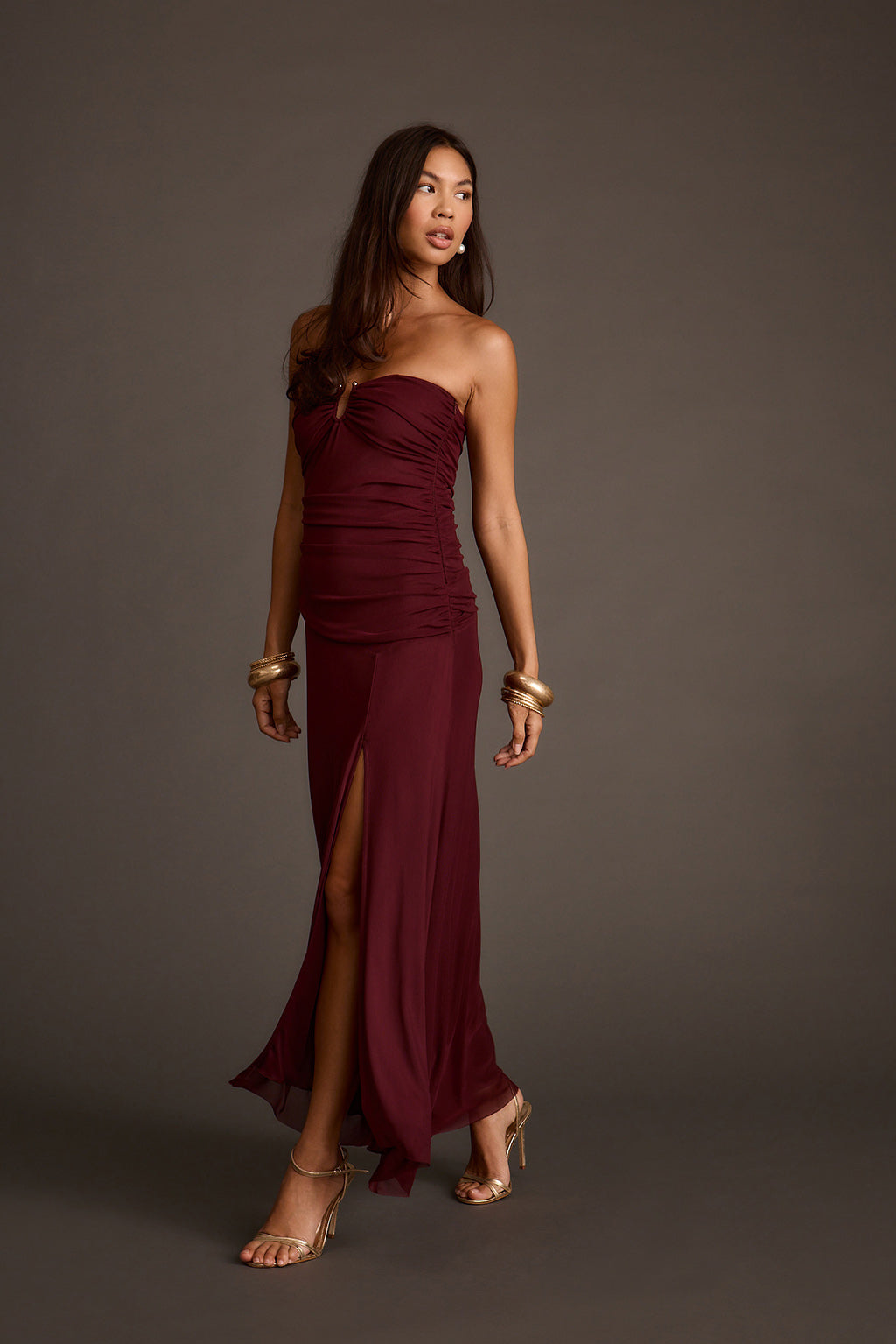 Burgundy strapless mesh maxi dress with a ruched bodice and thigh-high slit.