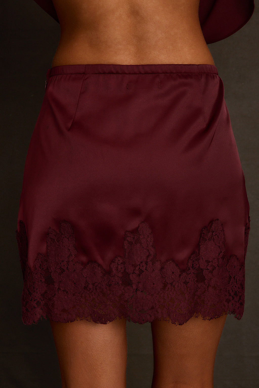Fall skirt back view showing pull-on fit and lace trim at hemline in mulberry satin