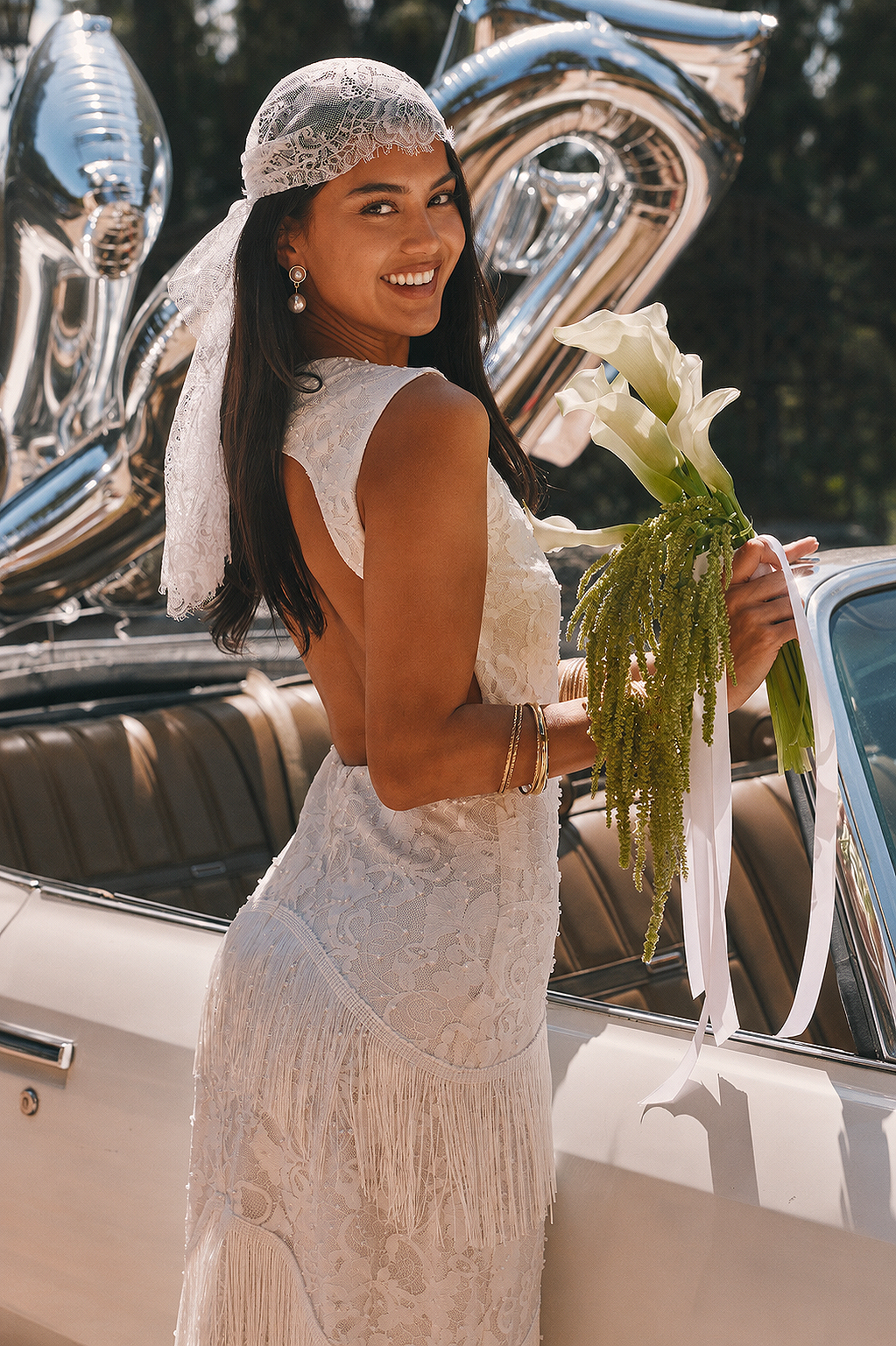 Back view of a lace kerchief headscarf worn with a fringed lace dress.