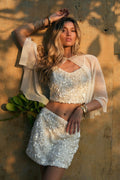 Model wearing the 12th Tribe Esme White Sequin Crop Top, featuring full chunky sequin embellishment and a cropped silhouette, styled with the Esme White Sequin Mini Skirt for bachelorette parties, weddings, concerts, and maybe even some vacation nightlife.
