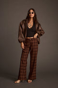 Full-length front view of a woman in mocha plaid wide-leg pants and a brown leather jacket