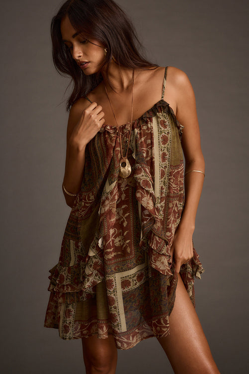 Woman wearing olive patchwork ruffle mini dress with tie-front detail, side view
