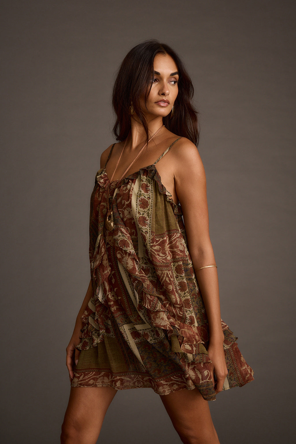 Woman wearing olive patchwork ruffle mini dress with spaghetti straps, front view