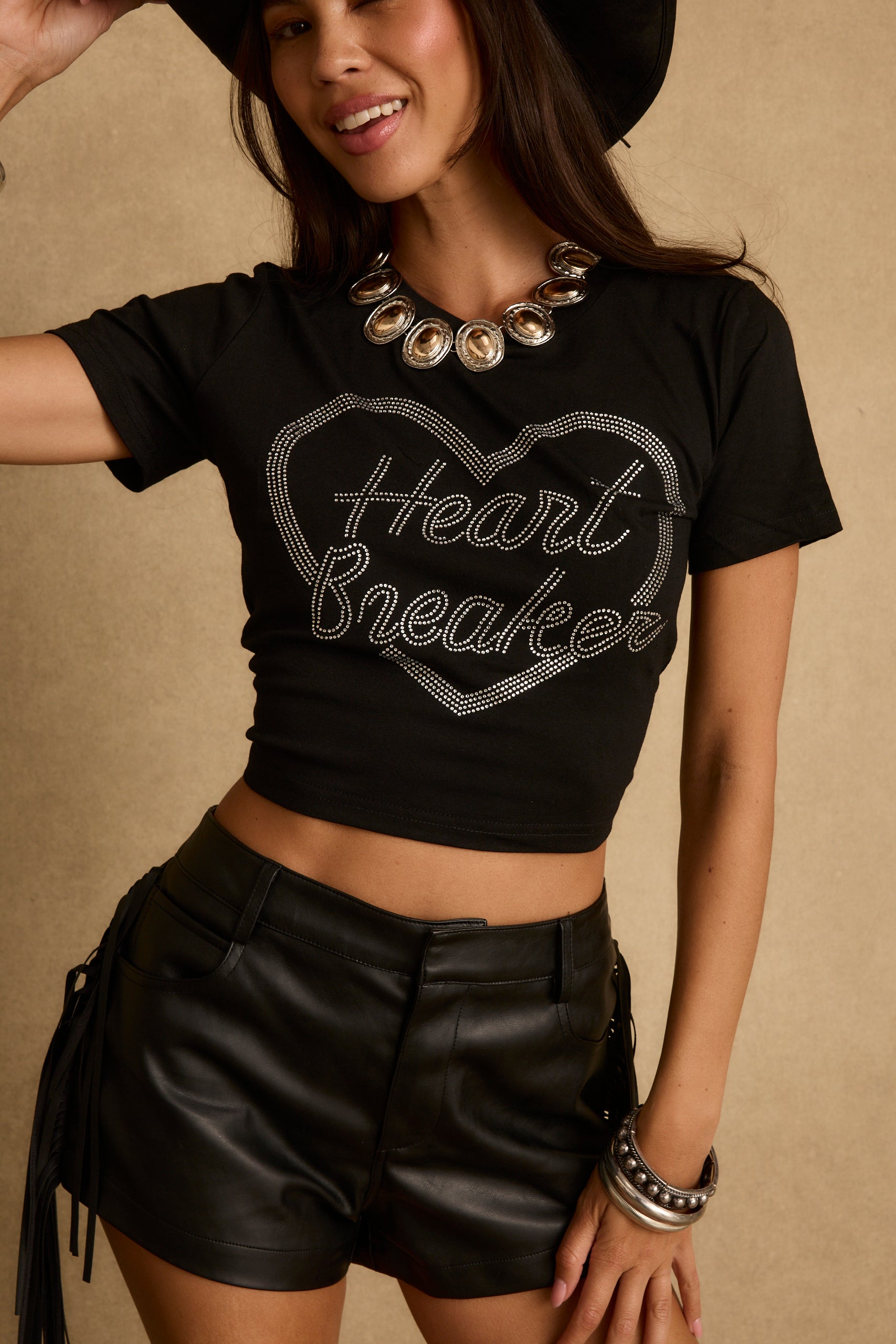 Model wearing the 12th Tribe Heartbreaker Black Rhinestone Graphic Tee, featuring a relaxed black tee silhouette with sparkling rhinestone lettering, styled with high-waisted jeans, shorts, or skirts for bachelorette parties, brunches, concerts, and casual everyday wear