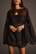 Close-up of a sheer black cover-up dress accessorized with a statement pendant necklace and gold cuffs