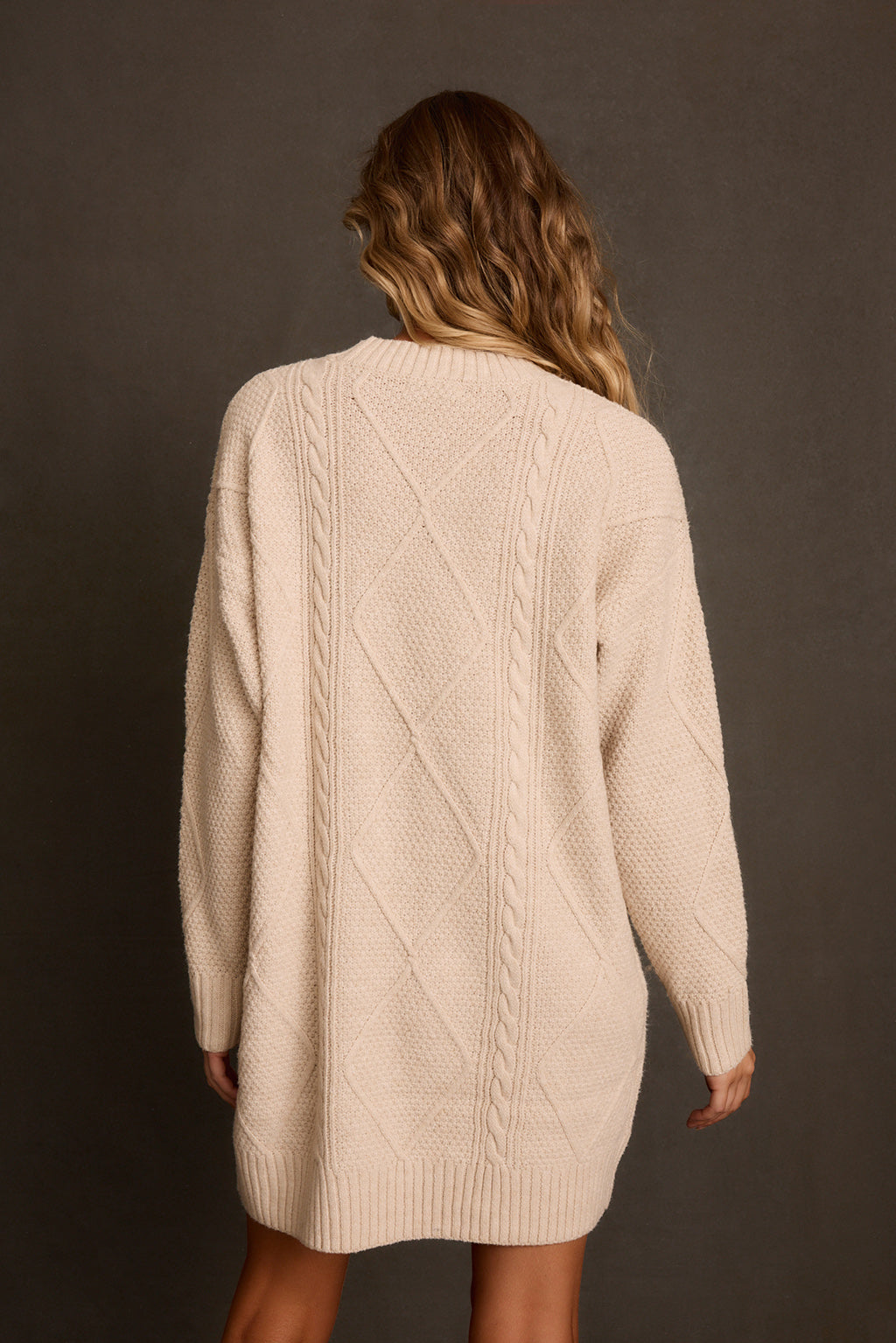 Cream sweater dress back view showing cable knit pattern and ribbed cuffs