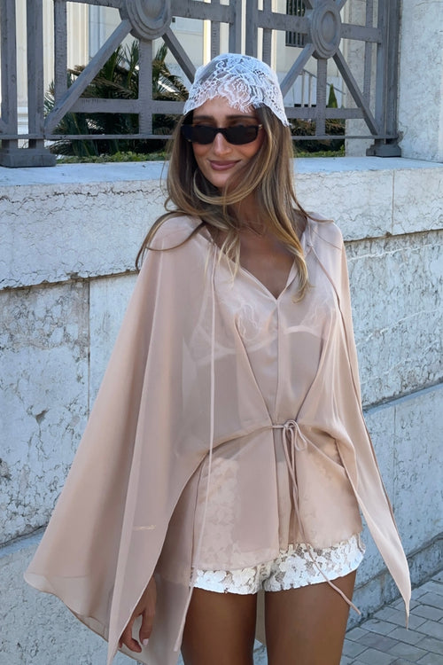 Sheer blush chiffon wide-sleeve cover-up styled with a white lace headscarf and sunglasses