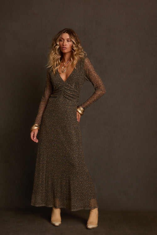 Women's maxi dress side view outdoors showing long sleeve fitted silhouette and floor length