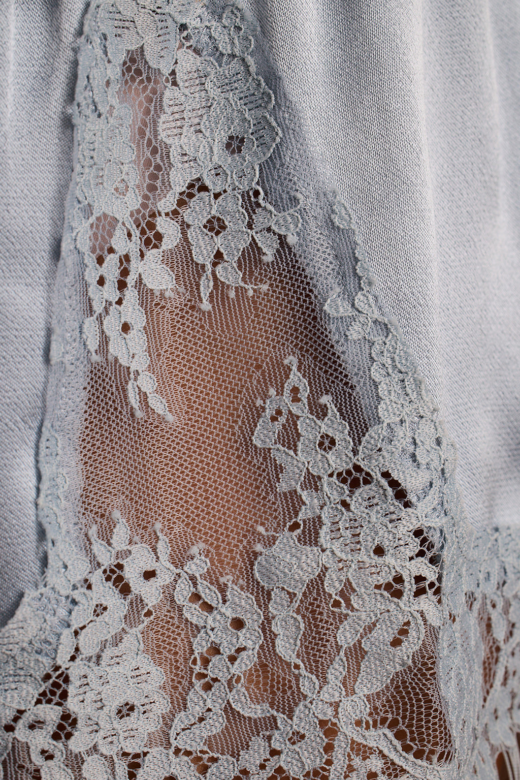 Close-up of sheer blue lace with a floral pattern layered over satin fabric.