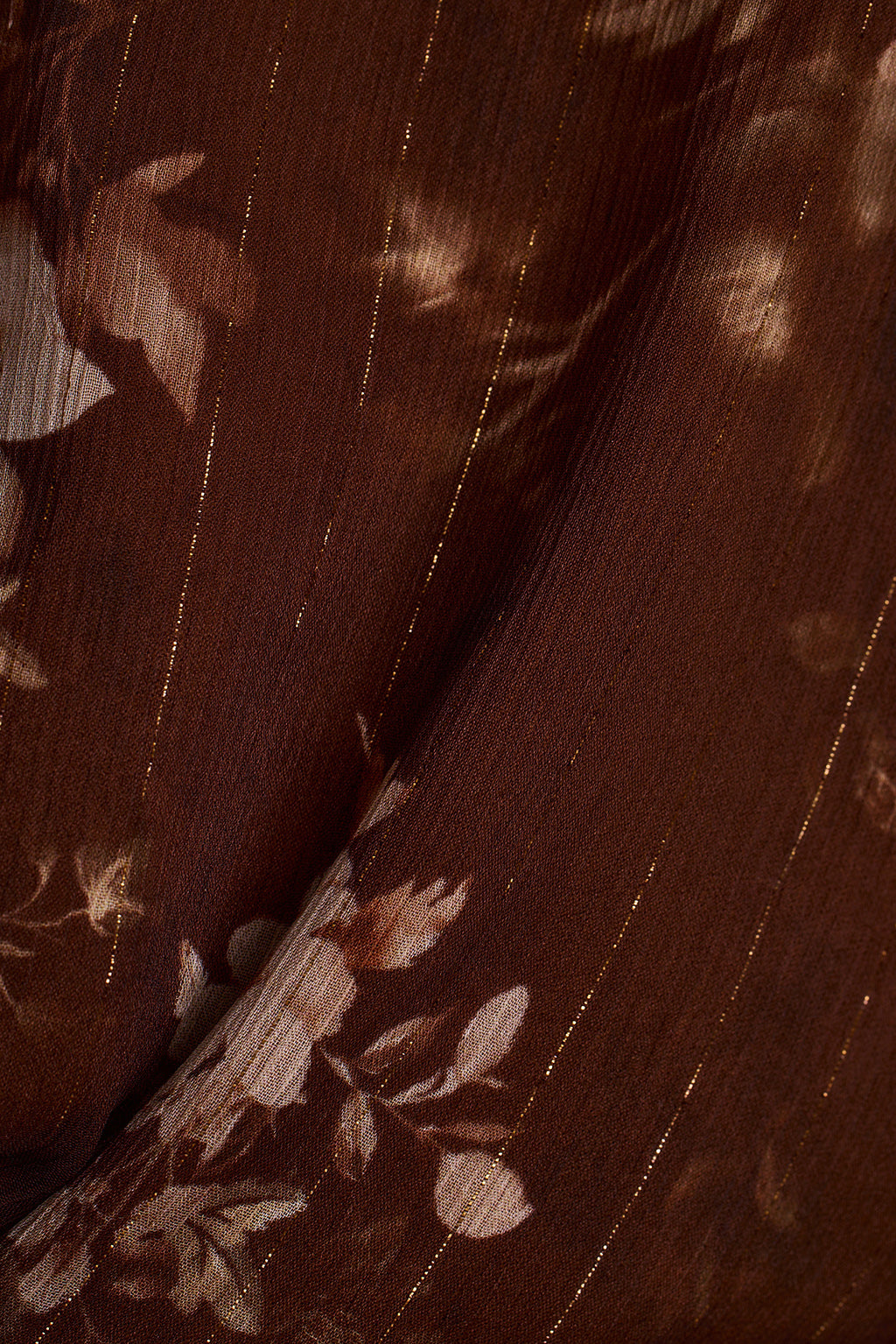 Close-up of brown floral chiffon fabric with metallic pinstripes.