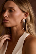Baroque pearl stud earring with a gold wire wrap frame and a multi-strand gold chain and pearl fringe.